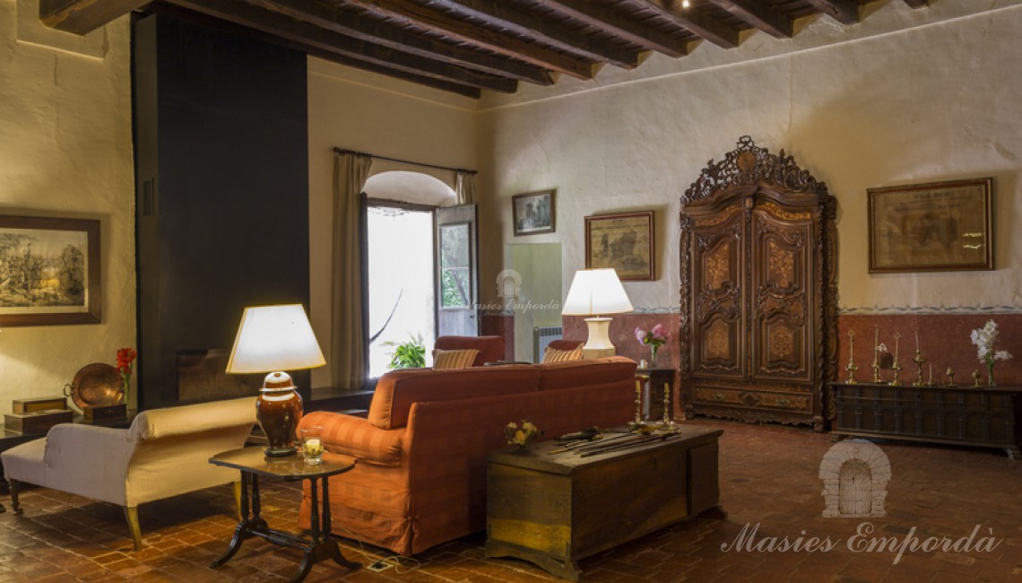 Salón principal de la masía con chimenea y acceso a la terraza de arcos de la fachada lateral 