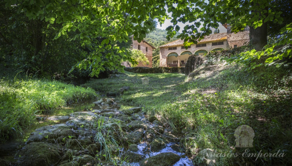 Desde el rio que fluye por la propiedad vista el conjunto constructivo de la masía. 