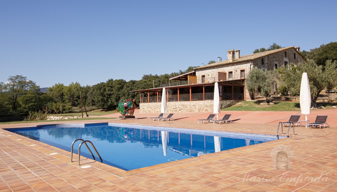 Vistes de la zona de piscina amb la masia el fons de la imatge