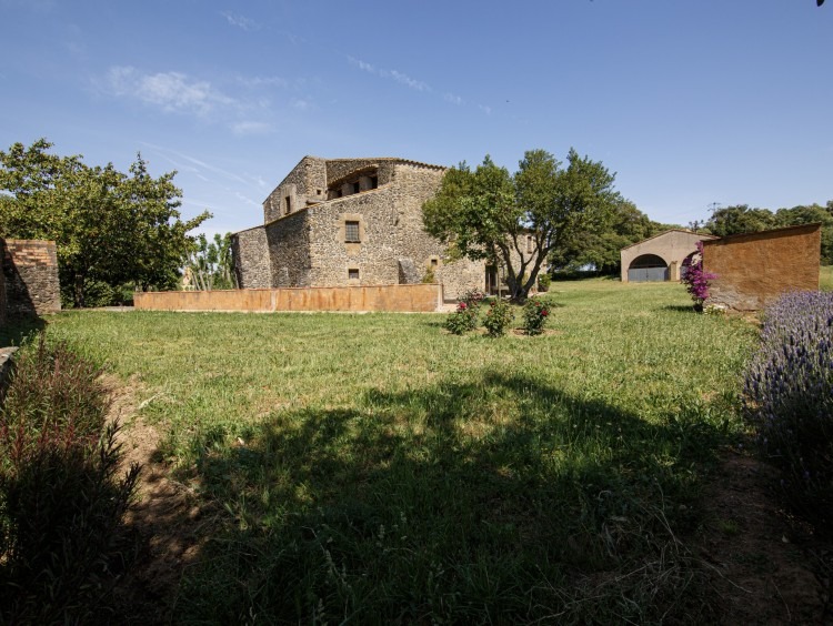 Vista general de la masia, jardí i paller al fons de la imatge