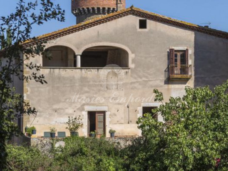 Vista desde el lateral de la masía donde se aprecia el volumen constructivo de la propiedad con el detalle de la torre redonda que sobresale de la cubierta a dos aguas de la masía  